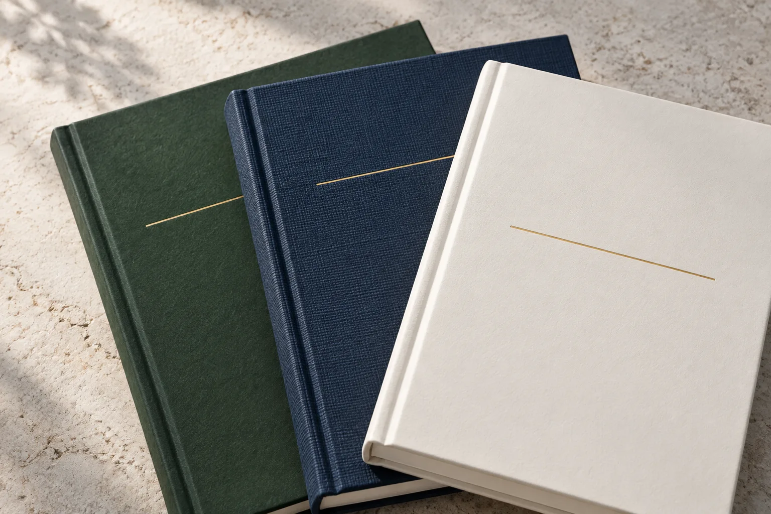 Three hardbound book covers with distinct paper and cloth-like finishes